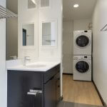 View of modern bathroom leading into walk-in closet with stacked washer-dryer