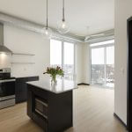 Interior apartment photo showing two floor-to-ceiling widows and open concept kitchen